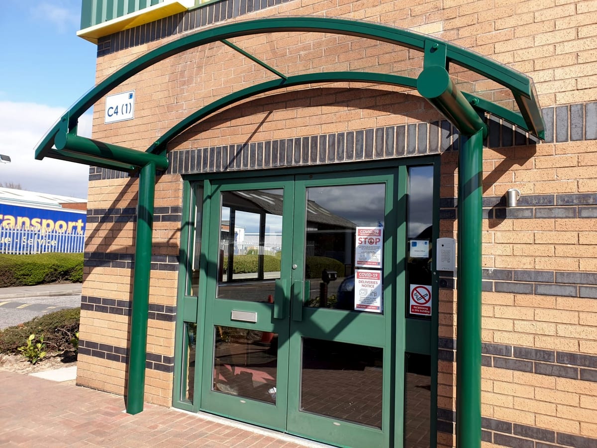 Arched entrance canopy in green powder-coated steel over an office entrance