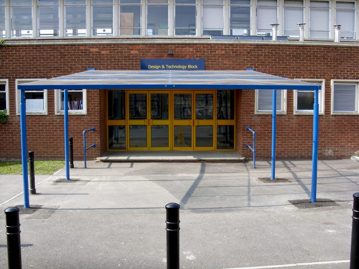 Flat entrance canopy in blue powder-coated steel over a school block’s double doors